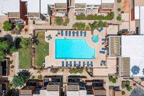 An aerial view of a hotel with a central swimming pool, multiple balconies, and surrounding greenery. - Dog Friendly - 2 Patios Heated Pool, Spa & Fitness (Scottsdale)