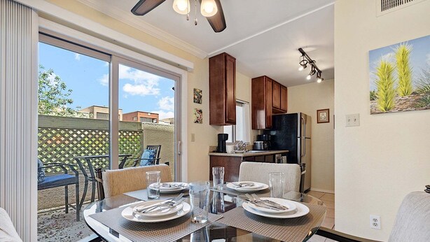 Un comedor con mesa de vidrio, sillas y una cocina al fondo.