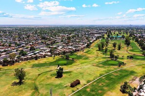 An aerial view of a residential area with houses, green spaces, and a golf course.