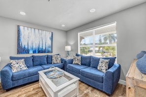 A living room with a blue sofa set, a coffee table, and a painting on the wall.