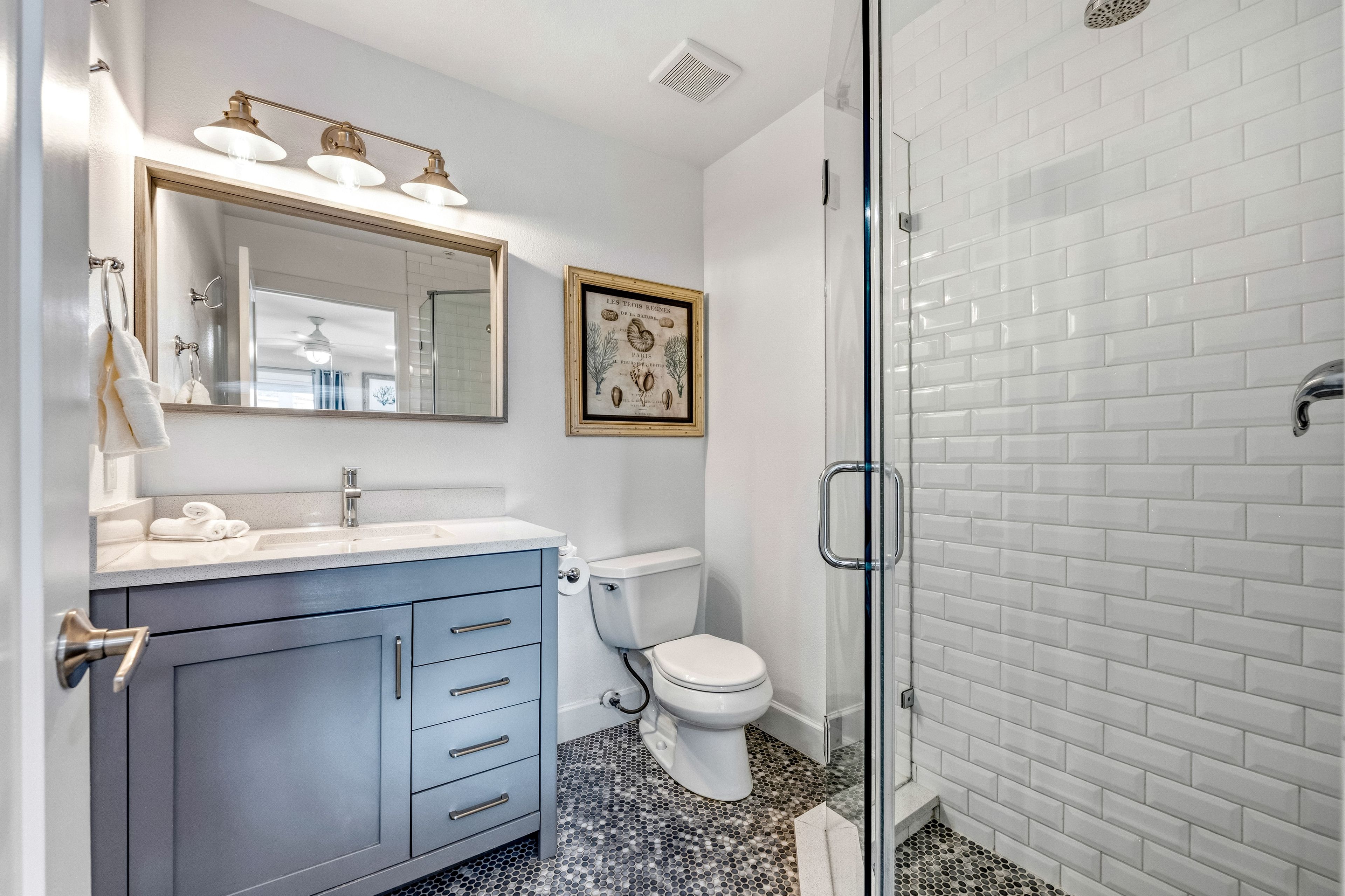 A bathroom with a white toilet, a sink with a mirror, and a shower area.
