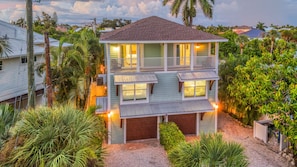 Une maison à deux étages dotée d’un balcon, entourée d’une végétation tropicale.