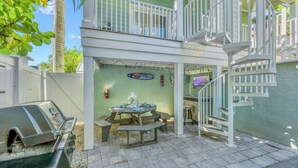 A patio area with a barbecue grill, picnic table, and a spiral staircase.
