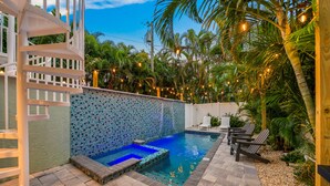 Una piscina con parete a mosaico, area relax all'aperto e luci decorative.
