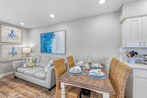 A dining area with a wooden table set for four, surrounded by wicker chairs.