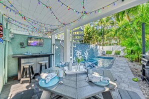 A patio area with a pool, bar, and seating.