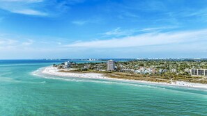 A coastal cityscape with a beach, buildings, and a clear sky.