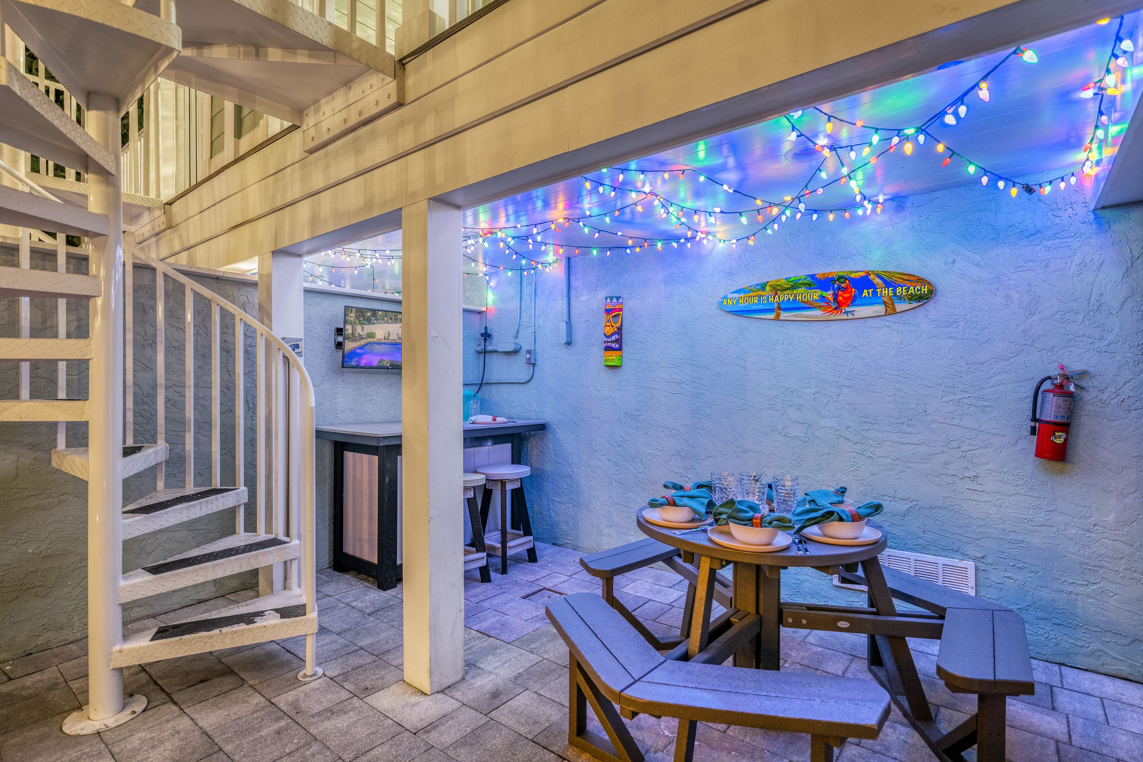 A pool area with a table and chairs, a fire extinguisher, and a staircase.