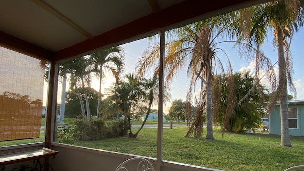 A room with a large window overlooking a grassy area with palm trees. - Vintage Vero Bungalow II (Vero Beach)
