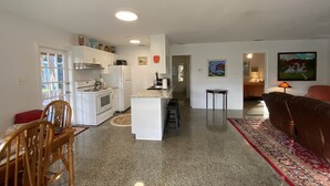A spacious living area with a kitchen, a dining table, and a sofa. - Vintage Vero Bungalow II (Vero Beach)
