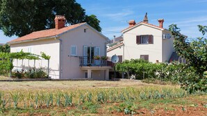 Una casa de dos pisos con techo de tejas rojas, un balcón con baranda metálica y una antena parabólica.