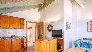 Una cocina con armarios de madera, salpicadero de azulejos, una isla de madera, un televisor y un sofá azul con estampado.