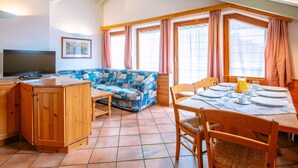 Una habitación acogedora con sofá, aparador de madera y mesa lista para el desayuno.