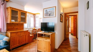 Une cuisine compacte avec des meubles en bois, un coin repas avec des chaises, un téléviseur et une petite table.