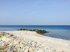 Una playa con costa rocosa y mar tranquilo.