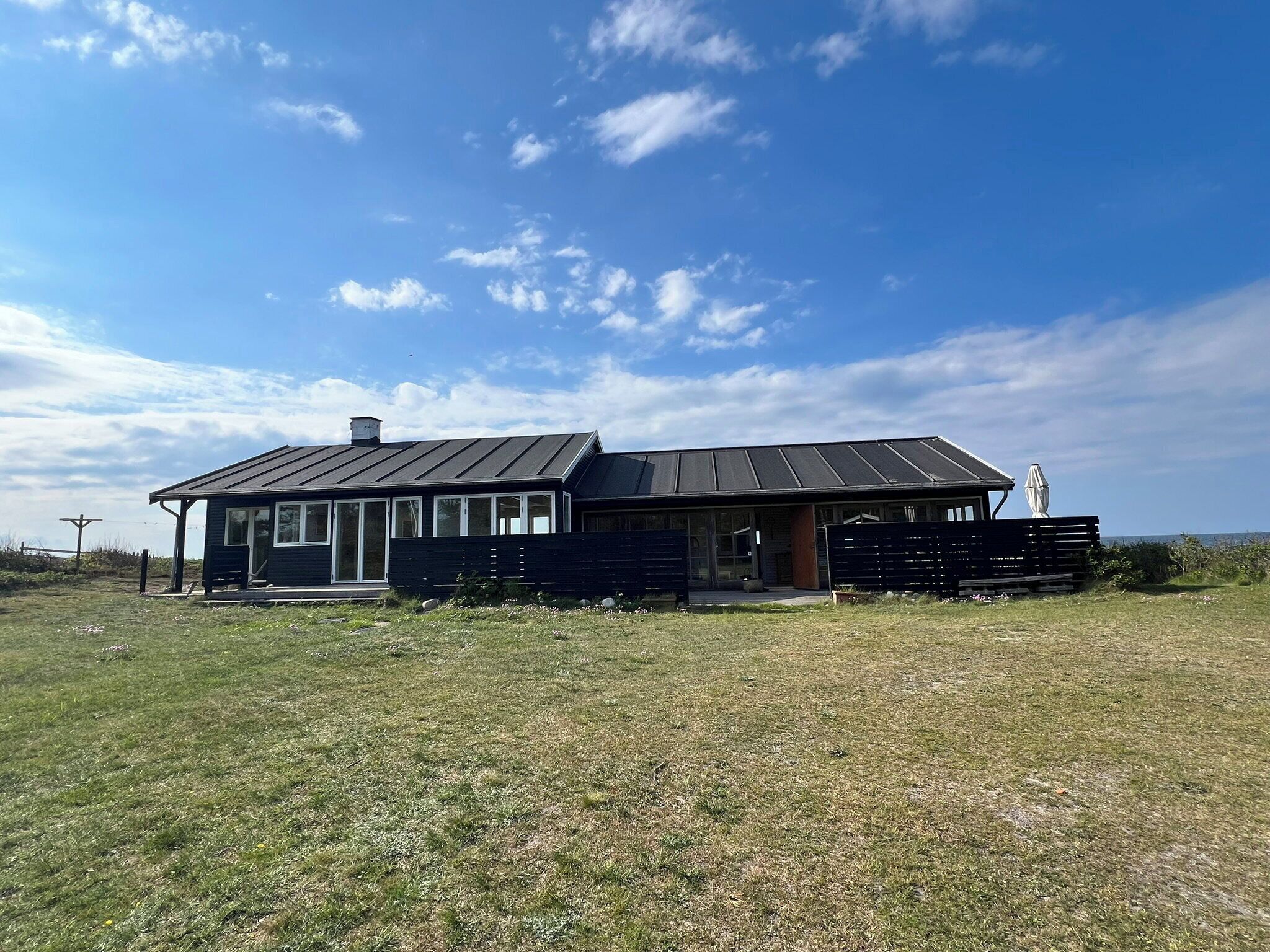 Une maison moderne à deux étages, dotée d’une grande terrasse, d’un porche couvert et offrant une vue sur l’océan.