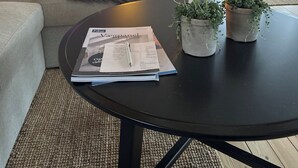 A living room with a sofa, a coffee table with a magazine, a TV, and a door leading to a balcony. - Cozy little holiday home near the beach (Otterup)
