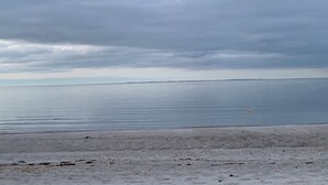 A beach with a calm sea and overcast sky. - Cozy little holiday home near the beach (Otterup)