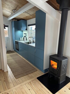 A modern kitchen with blue cabinets, a black stove, and a wooden floor.