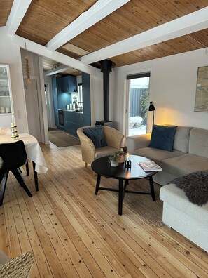 Uma sala de estar moderna com piso de madeira, um sofá, uma mesa de centro e um espaço de jantar com mesa e cadeiras.