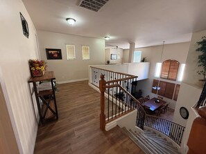A spacious living area with a wooden floor, a staircase with a wooden railing, and a dining area with a table and chairs. - Castillo Royal Heated Pool (Casa Grande)