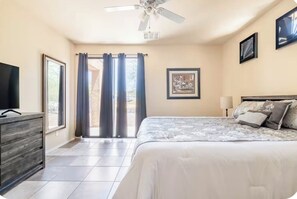 A bedroom with a bed, a television, a ceiling fan, and a window with curtains. - Castillo Royal Heated Pool (Casa Grande)