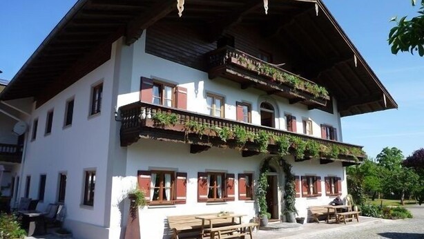 Un bâtiment à deux étages doté d’un balcon à l’étage supérieur, d’une terrasse et d’une entrée pavée de pierres.