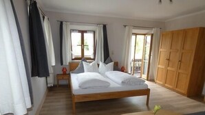 Une chambre à coucher avec un lit en bois, une table de chevet avec une lampe, une petite table ronde avec une plante et une armoire.
