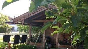 Un patio couvert avec une balançoire, un petit jardin et une structure en bois.