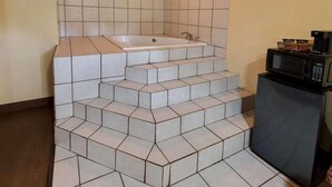 Kylpyhuone, jossa on kylpyamme, mikroaaltouuni ja jääkaappi.