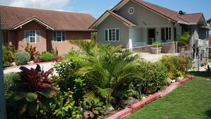 A residential area with two houses, a well-maintained garden, and a clear sky. - Soleil Hartland 122 (St. Ann's Bay)