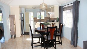 A spacious dining area with a round table, chairs, and a chandelier. - Soleil Hartland 122 (St. Ann's Bay)