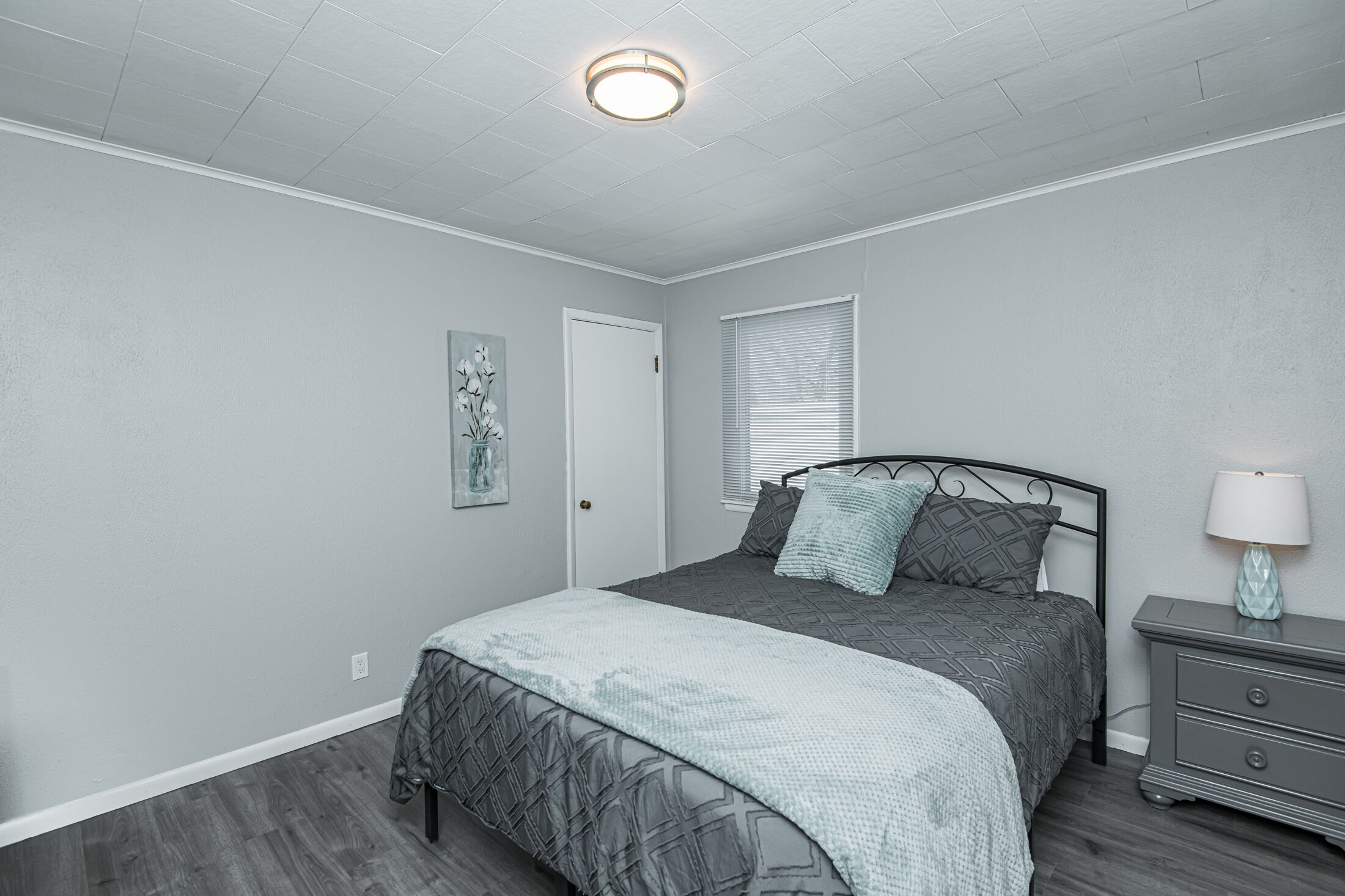 A bedroom with a bed, nightstand, and a wall-mounted light fixture.