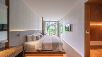 A modern bedroom with a large bed, built-in TV, and a view of greenery outside.