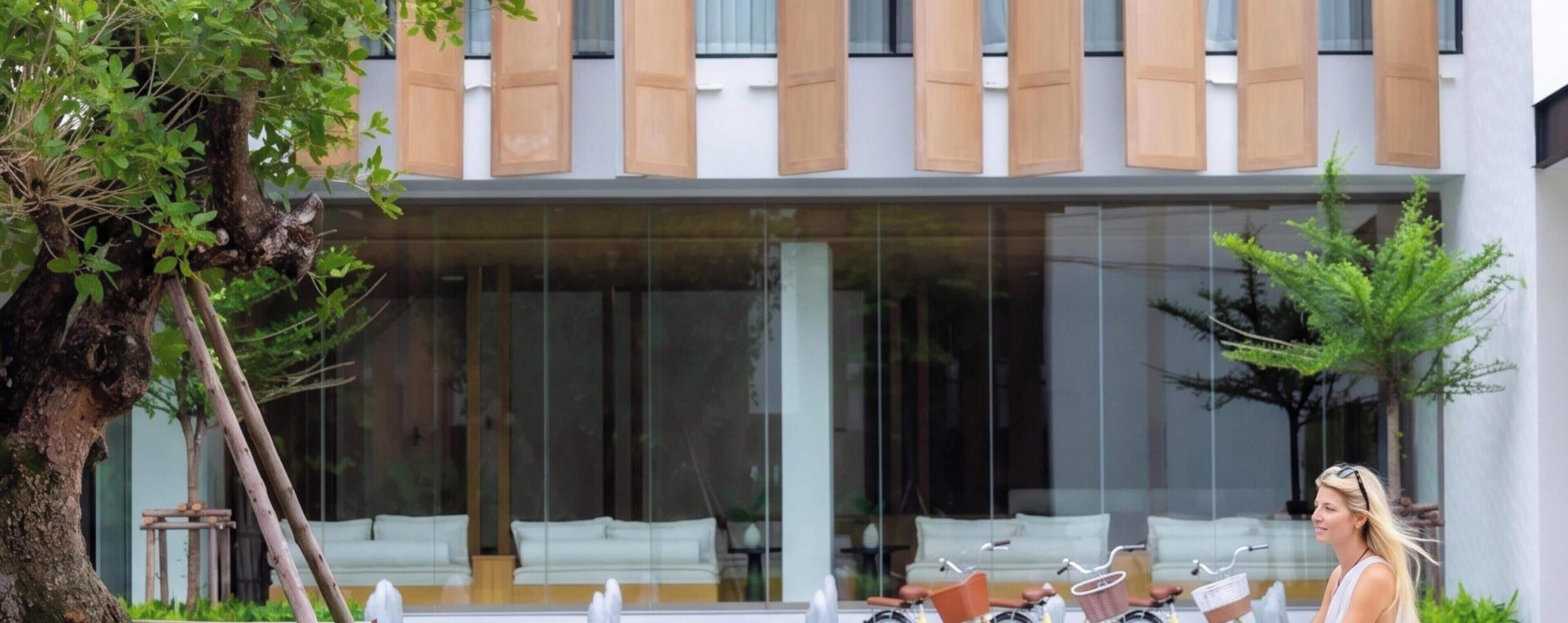 A modern building with large glass windows, wooden shutters, and outdoor seating.