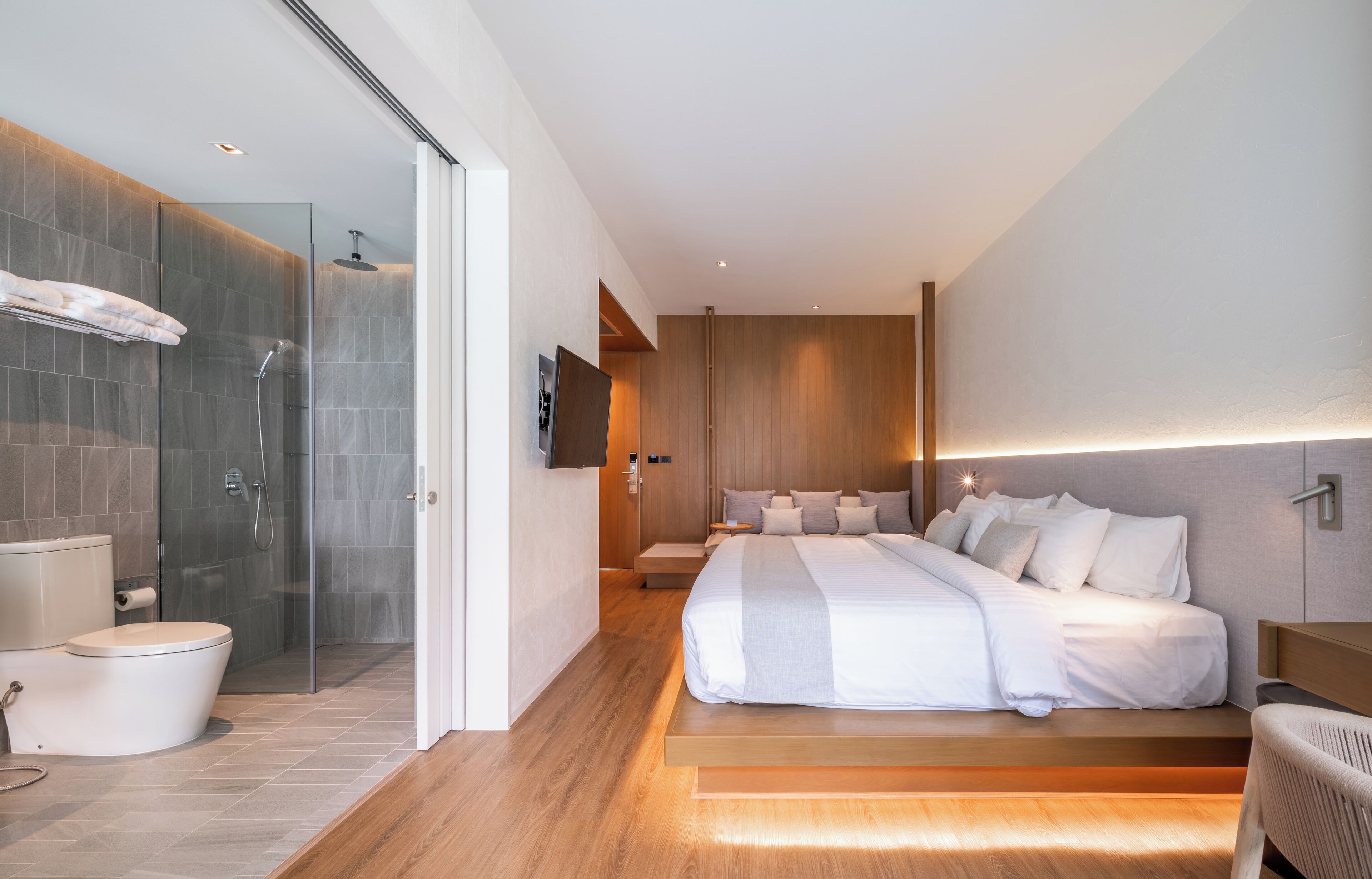 Une chambre moderne avec un grand lit, une table de chevet et un espace douche.