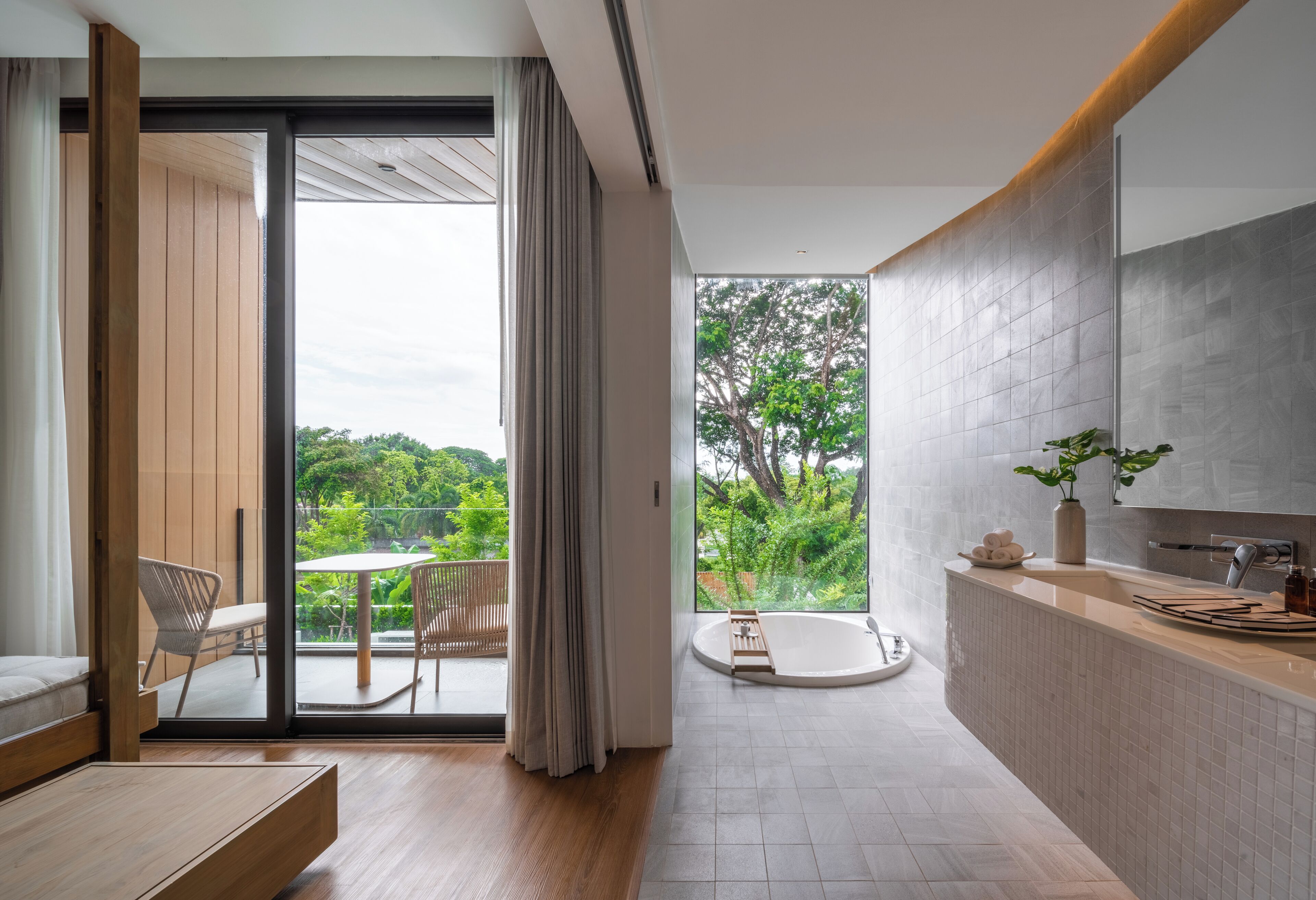 Un baño moderno con bañera, lavamanos y ventana con vistas a la vegetación.