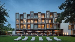 A modern hotel with multiple balconies, outdoor seating, and a well-maintained lawn. - Riva Vista Riverfront Resort Chiangrai (Chiang Rai)