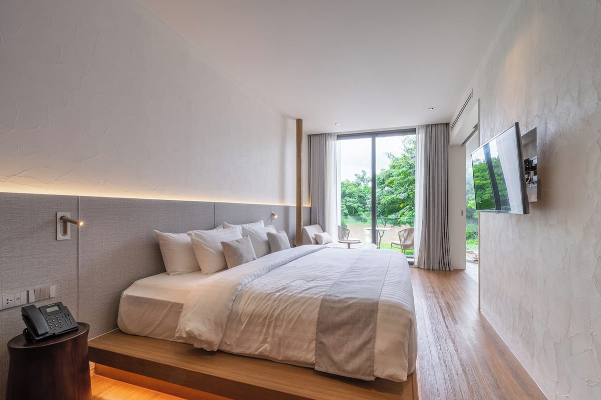 A modern hotel room with a large bed, a bedside telephone, and a television mounted on the wall.