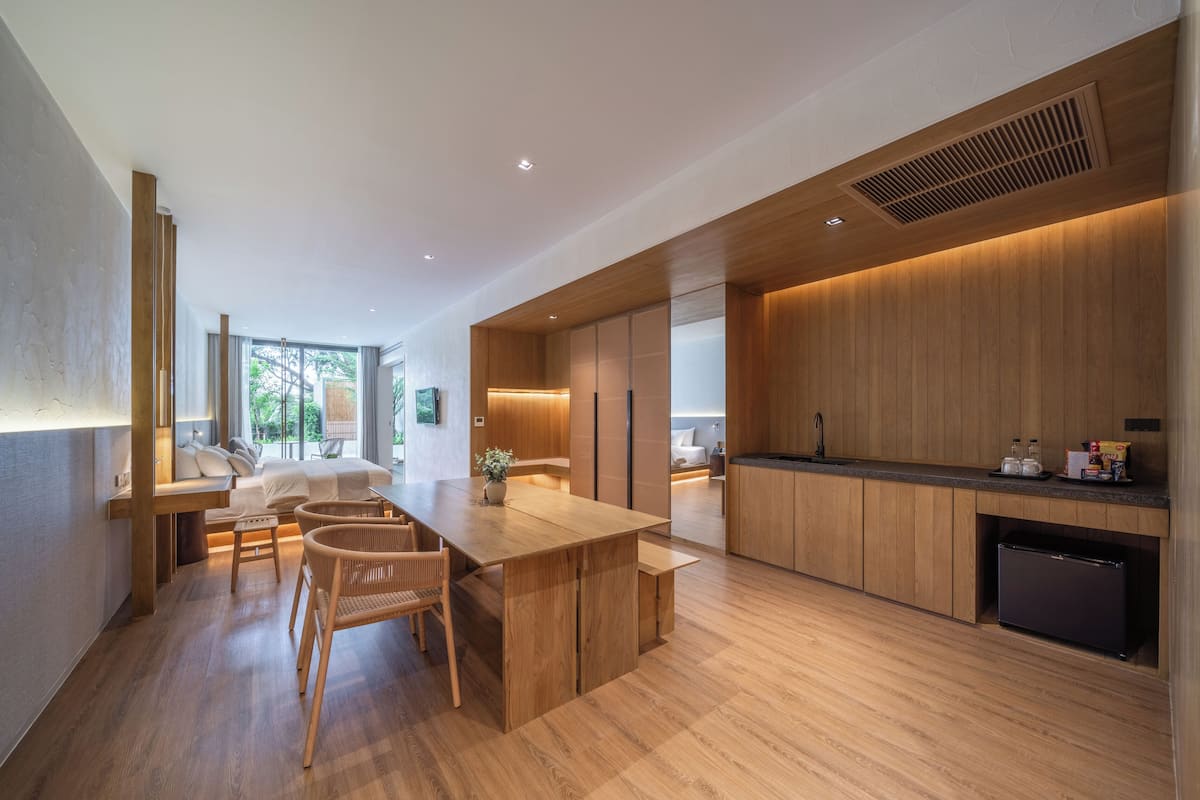 A modern kitchen with wooden cabinetry, a central island, and a dining area with chairs.