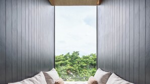 A room with a large window, a cushioned seating area, and wooden panel walls. - Riva Vista Riverfront Resort Chiangrai (Chiang Rai)