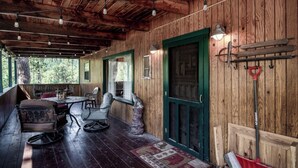 Une cabane en bois avec une véranda, une table à manger avec des chaises et une porte verte.