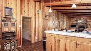 Un intérieur rustique avec des éléments en bois, notamment un coin cuisine, des placards en bois et une cheminée en pierre.