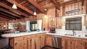Une cuisine de style rustique, avec des meubles en bois, un lave-vaisselle en acier inoxydable et une machine à café.