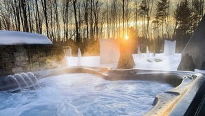 A hot tub surrounded by snow and trees with a sunset in the background. - Le Camp Caché Shefford (Shefford)