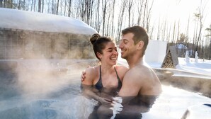 A couple in a hot tub surrounded by snow and trees. - Le Camp Caché Shefford (Shefford)
