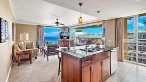 A spacious living area with a large island kitchen, a dining area, and a view of the ocean.