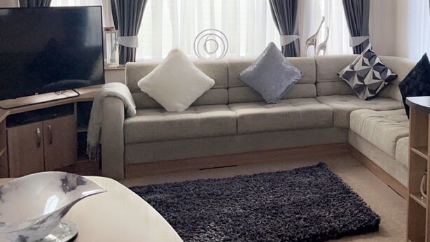 Un salon moderne avec un canapé, un téléviseur à écran plat et un vase décoratif posé sur une table.