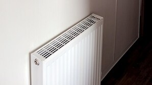 Un couloir avec deux dessins linéaires encadrés accrochés au mur et un radiateur blanc en bas.