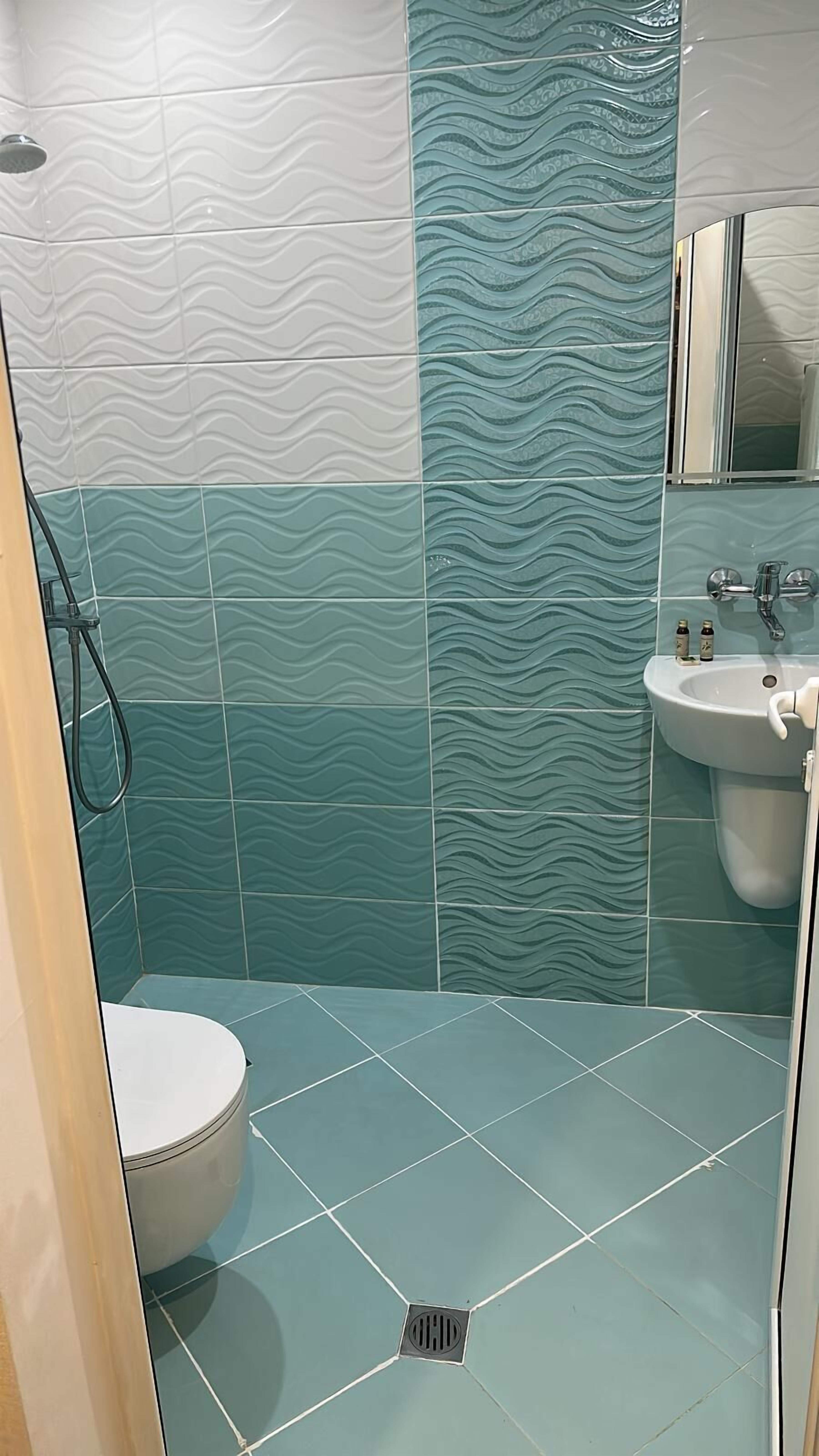 A bathroom with a toilet, sink, and shower area.